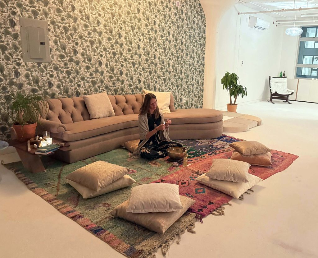 Fede sitting on a mat in a studio surrounded by pillow settings.
